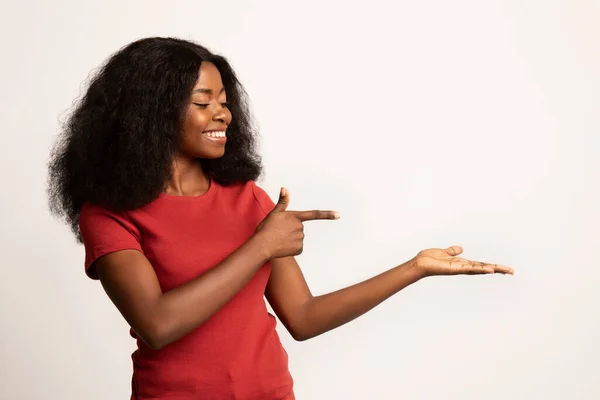 Отличное предложение. Радостная афроамериканка, указывающая на свою открытую пустую ладонь — стоковое фото