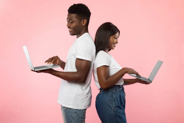 Pareja afroamericana usando teléfonos inteligentes, pared de estudio rosa —  Fotos de Stock
