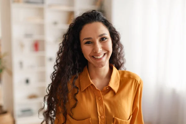 Šťastná středovýchodní podnikatelka v košili s úsměvem na kameru uvnitř — Stock fotografie