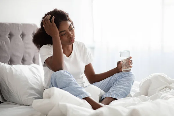 Sick african american lady feeling bad, touching head, bedroom interior — Stock Photo, Image