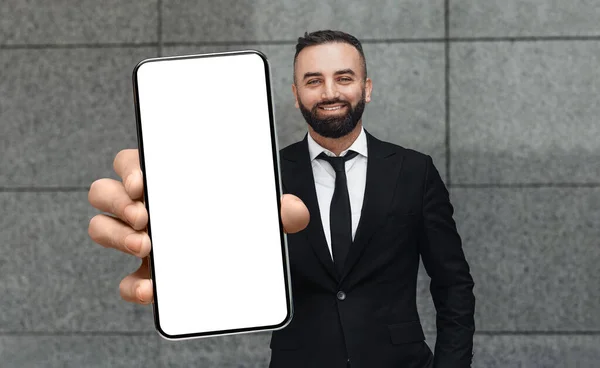 Schöner Geschäftsmann mittleren Alters im Anzug demonstriert große leere Smartphone, Attrappe — Stockfoto