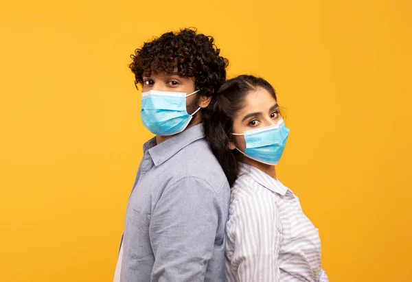 一起与大流行病作斗争。年轻的印第安夫妇戴着防护口罩，背靠背地站着 — 图库照片