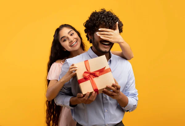 Jolie femme indienne couvrant ses yeux de copains, tenant une boîte-cadeau et le saluant avec anniversaire ou anniversaire — Photo