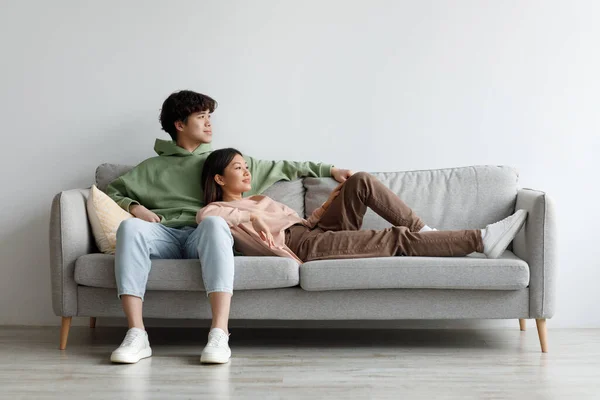 Romântico jovem casal asiático relaxante no sofá na sala de estar, passar o tempo juntos, espaço de cópia — Fotografia de Stock