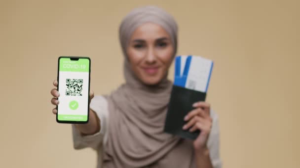 Mladá turistka ze Středního východu s pasem a lístky na Covid-19 očkovací průkaz na smartphonu