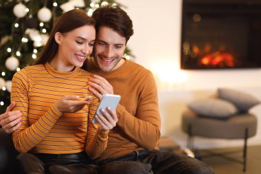 Mutlu çift cep telefonu kullanıyor ve evde konuşuyor.