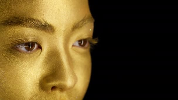 Kvinna med gyllene hud tittar bort på svart bakgrund, beskuren — Stockvideo