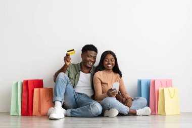 Duygusal Afrikalı Amerikalı çift akıllı telefon ve kredi kartı kullanıyor.