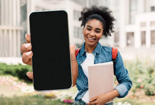 Mobile Mockup. Allegra studentessa nera che dimostra grande smartphone vuoto alla fotocamera — Foto Stock