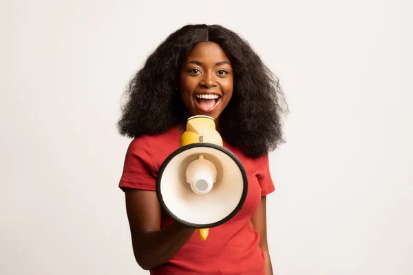 Веселая молодая афроамериканская женщина делает объявление с громкоговорителем — стоковое фото