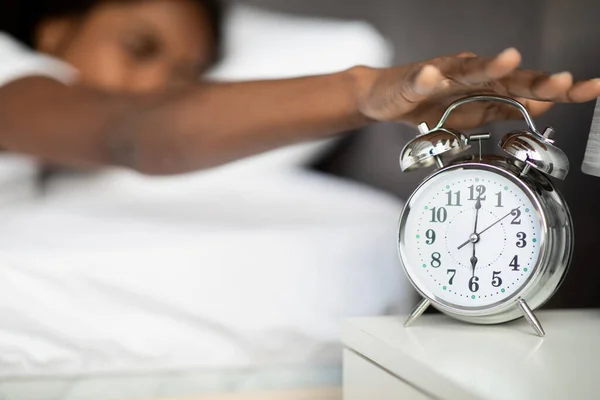 Donna nera sdraiata a letto, spegnendo l'allarme sul comodino — Foto Stock