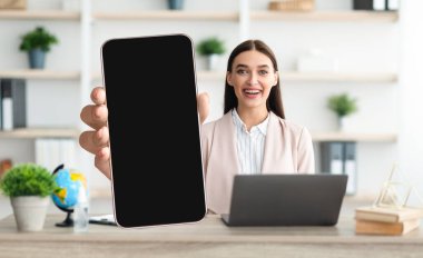 Mobil Model. Gülümseyen Kadın Ofiste Otururken Büyük Boş Akıllı Telefonu Gösteriyor