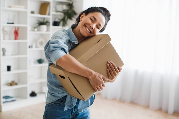 Alegre cliente mujer sosteniendo la caja de cartón y abrazándola en interiores —  Fotos de Stock