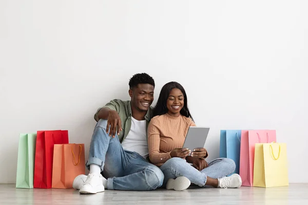 Hermosos amantes negros usando tableta digital, compras en línea —  Fotos de Stock