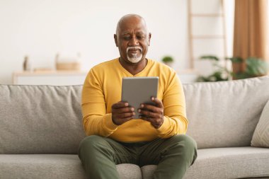 Kıdemli Afro-Amerikan Erkek Dijital Tablet Kullanan Salon İçi Okuma