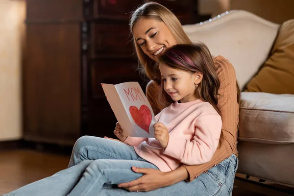 Feliz hija saludando a mamá con tarjeta, leyendo juntos — Foto de Stock