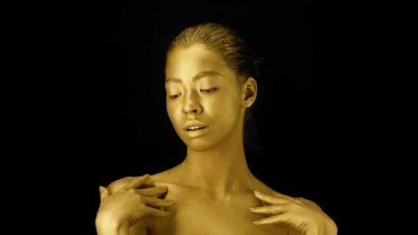 Женщина с трогательной шеей из золотой кожи на черном фоне — стоковое видео