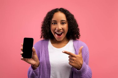 Harika bir teklif. Heyecanlı siyah kadın cep telefonunu boş ekran ile gösteriyor, yeni uygulama veya web sitesi reklamı yapıyor