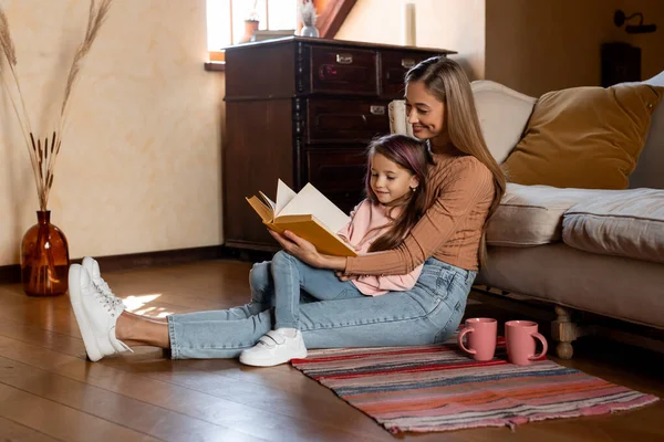 Retrato de madre e hija felices leyendo el libro juntas —  Fotos de Stock