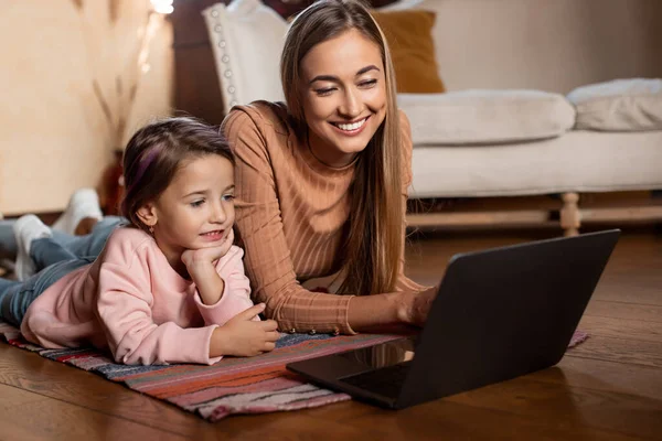 Smiling woman and girl using laptop at home — Stock Photo, Image