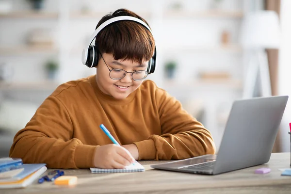 Sorridente asiatico ragazzo schooler avendo online lezione da casa — Foto Stock