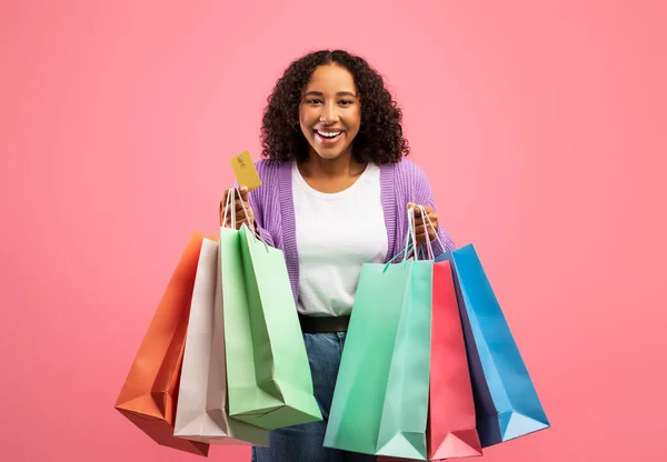 Απρόσκοπτη ιδέα αγορών. Χαρούμενη νεαρή μαύρη γυναίκα που κρατάει τσάντες και πιστωτικές κάρτες, διαφημίζοντας μεγάλη πώληση — Φωτογραφία Αρχείου