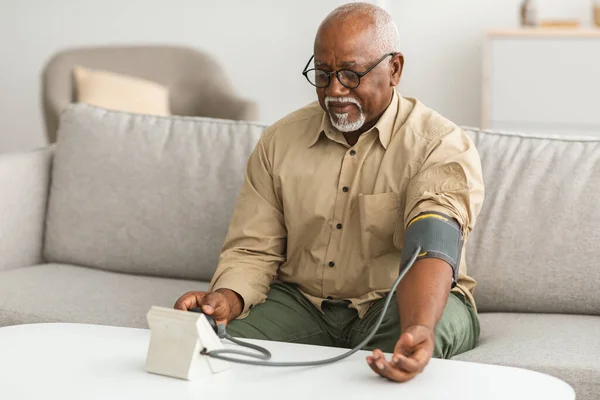 Senior Black Man misurazione della pressione arteriosa seduta a casa — Foto Stock