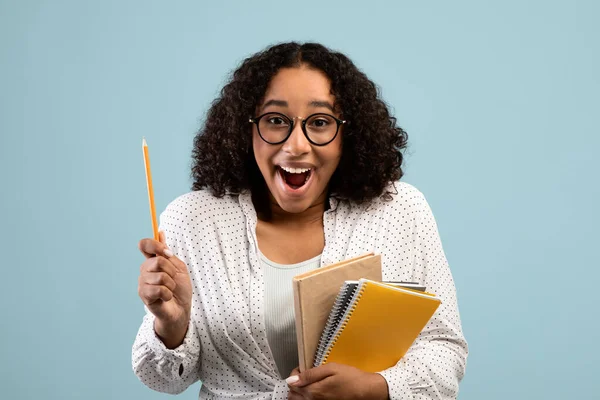 Cool black female student with study materials having creative idea, pointing upwards, experiencing AHA moment — Stock Photo, Image