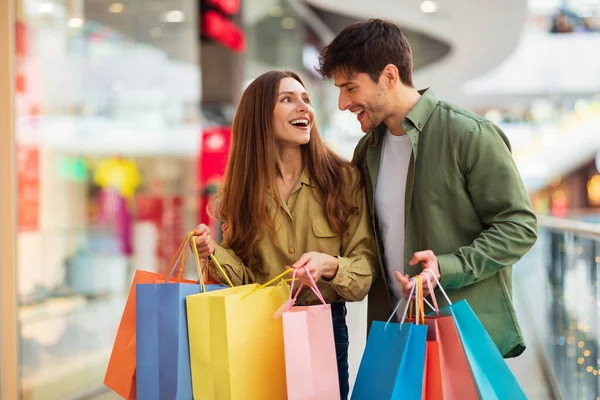 Alegre pareja en compras riendo celebración Shopper bolsas en hipermercado —  Fotos de Stock