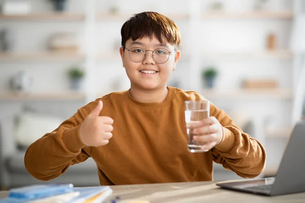 Zdrowy japoński nastolatek trzyma szklankę wody podczas nauki — Zdjęcie stockowe