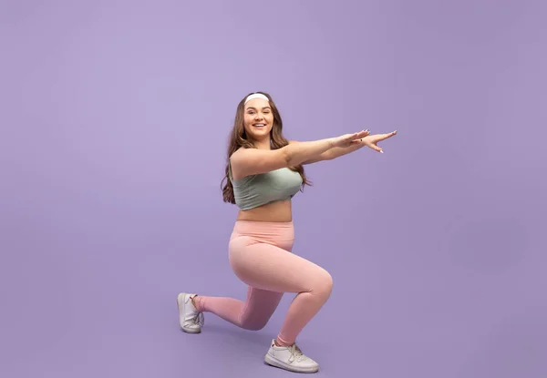 Sorridente felice caucasico plus size giovane donna in abbigliamento sportivo fare esercizi affondo — Foto Stock