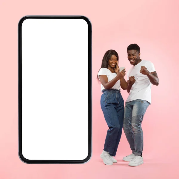 Ζευγάρι δείχνει λευκό κενό οθόνη smartphone και κάνοντας χειρονομία νίκη — Φωτογραφία Αρχείου