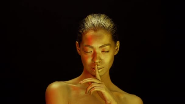 Mujer atractiva con la piel dorada Gesturing Hush Sign, fondo negro — Vídeos de Stock