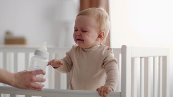 Pequeño bebé llorando mientras está de pie en la cama, madre irreconocible calmante niño molesto — Vídeos de Stock