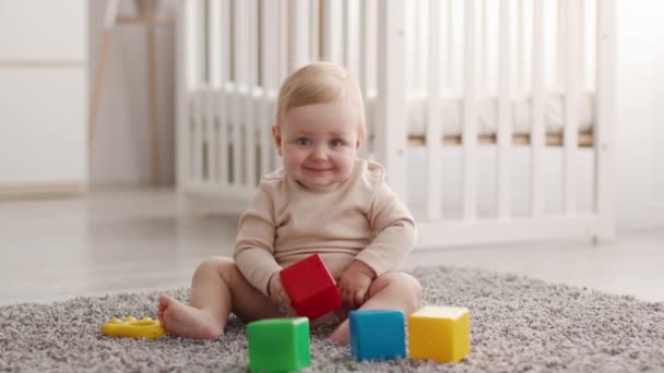 Kindervrijetijdsbesteding. Schattig klein baby zitten spelen met bouwstenen thuis — Stockvideo