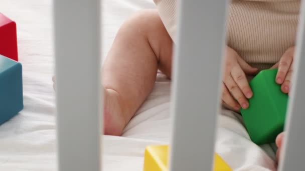 Bebek Yatakta Oturuyor ve Renkli İnşaat Bloklarıyla Oynuyor. — Stok video