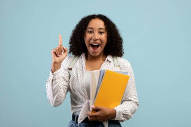 Heyecanlı genç siyahi kadının harika bir fikri var. Probleme ilham ya da çözüm buluyor. Açık ağızla poz veriyor.