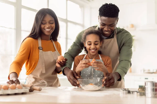 Feliz familia afroamericana horneando pasteles añadiendo huevos en la cocina — Foto de Stock