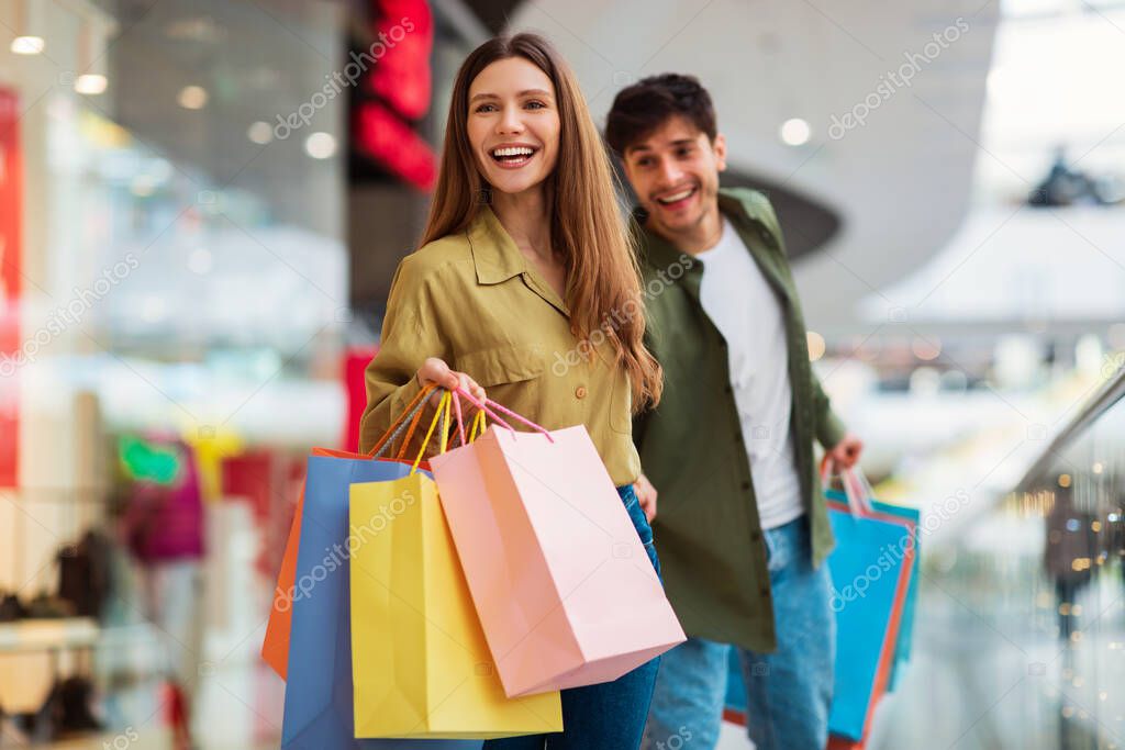 Couple Shopping Walking Carrying Colorful Shopper Bags In Mall