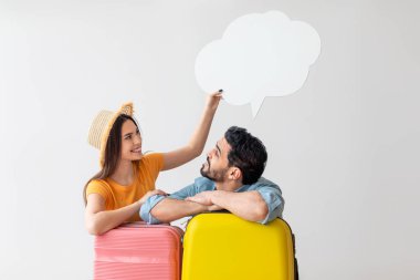 Seyahat teklifi. Bavulları olan mutlu genç bir çift, boş konuşma balonunu kocalarının kafasının üstünde tutan bir kadın, boş bir alan.