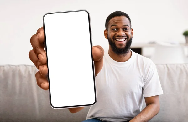 Мобильная реклама. Веселый черный мужчина держит пустой смартфон с большим белым экраном — стоковое фото