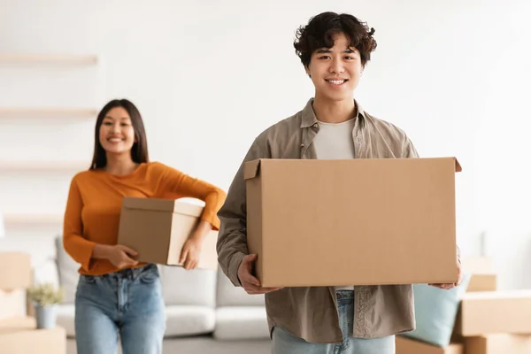 Beau jeune homme asiatique avec sa charmante petite amie portant des boîtes en carton, déballer dans leur nouvelle maison, espace de copie — Photo