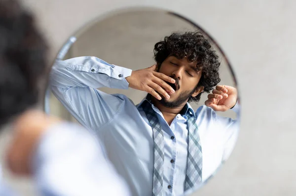 Homem de negócios indiano sonolento bocejando enquanto estava de pé no banheiro e olhando para seu reflexo no espelho — Fotografia de Stock