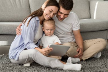 Anne babasıyla evde dinlenirken dijital tablet kullanan sevimli çocuk.