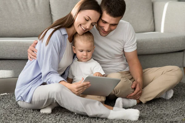 Ragazzo infantile carino che utilizza la tavoletta digitale mentre si rilassa con i genitori a casa — Foto Stock