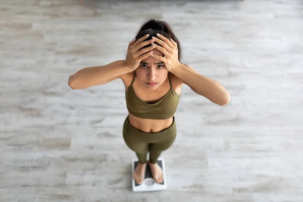 Skrämd ung indisk kvinna står på skalor, hålla huvudet i besvikelse, misslyckas med att uppnå viktminskning resultat — Stockfoto
