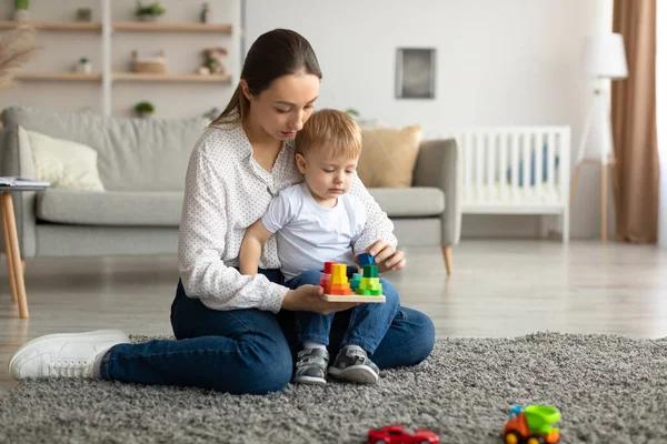 Gelukkig jong moeder en haar peuter zoon bezig met een interessant spel, het spelen van educatieve spelletjes samen — Stockfoto