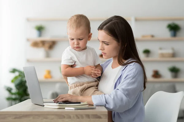 Working Mom. Frau benutzt Laptop zu Hause und kümmert sich um Baby — Stockfoto