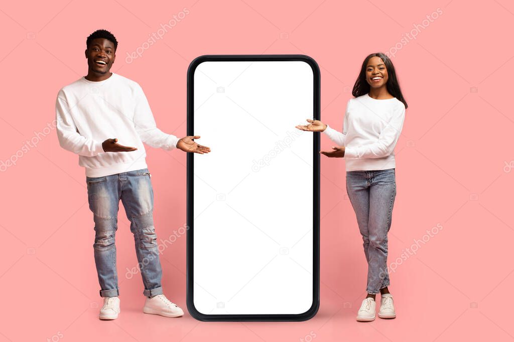 Positive african american couple posing with big smartphone, mockup