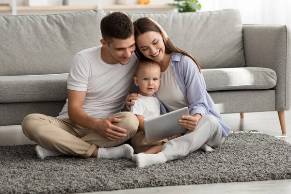Família jovem feliz de três com filho infantil relaxante com tablet digital — Fotografia de Stock
